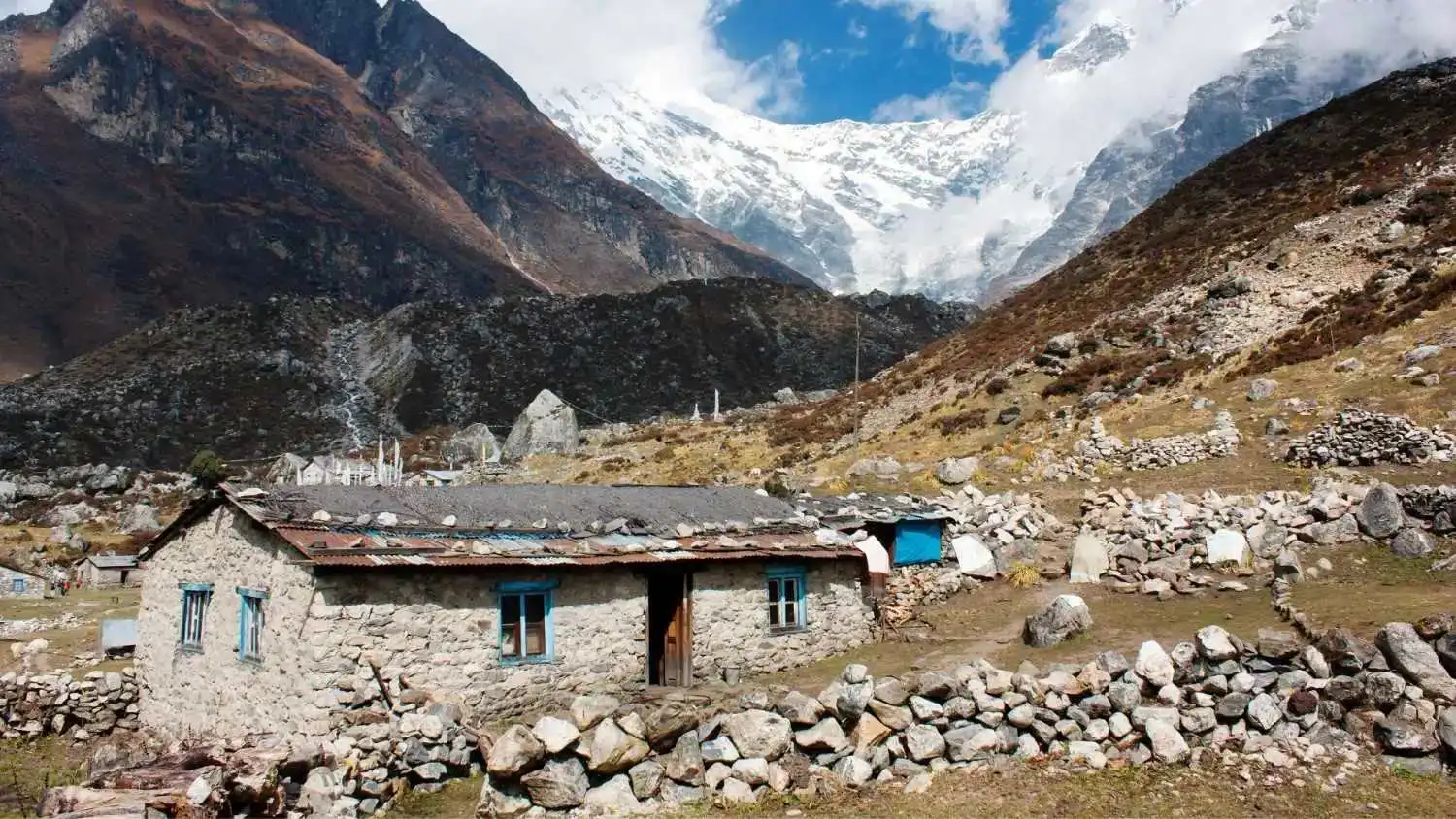 Traditional stone house in Langtang Valley surrounded by rugged Himalayan terrain and snow-covered mountains