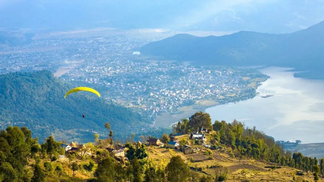 Paraglider flying over the hills and Phewa Lake with Pokhara city in the background